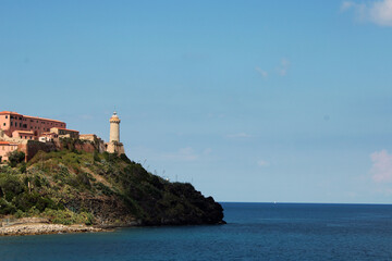 Fototapeta na wymiar Faro marittimo sulla punta del promontorio con cielo e orizzonte