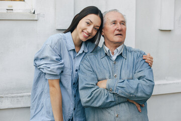 Grandfather on a gray background. Old man with granddaughter. Senior in a blue shirt.