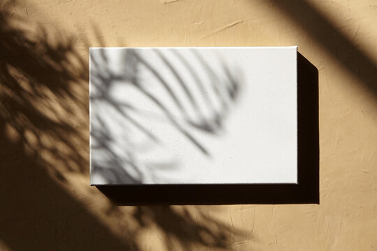 White blank canvas hanging on wall with shadows. Mockup