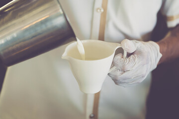 Close-up of Barista working with gloves while pouring hot milk for prepare coffee latte art, Protective measures at work during a Covid-19 outbreak. vintage film color tone.