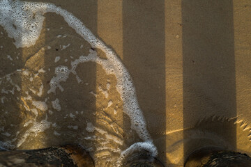 Top view of the sea. Sandy beach. Shadows from the bridge.
