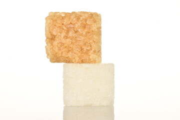 Two cubes of brown and white sugar, close-up, on a white background.