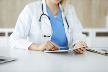 Unknown woman-doctor standing in clinic and using tablet pc, close-up. Data and best service in medicine and healthcare