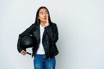 Fototapeta premium Young asian woman holding a motorbike helmet over isolated background is saying a secret hot braking news and looking aside