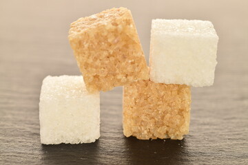 Several cubes of brown and white sugar, close-up, on a slate board.