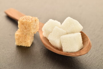 Several cubes of brown and white sugar, close-up, on a slate board.