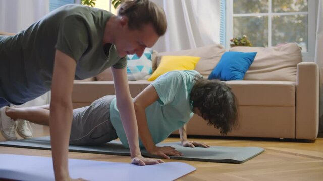 Two young men doing push-ups exercise working out at home.