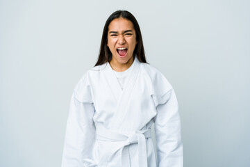 Young asian woman doing karate isolated on white background screaming very angry and aggressive.