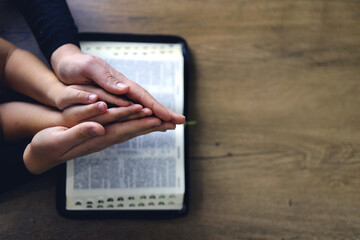 Religious Christian girl praying with her mother indoors
