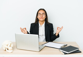 Young traumatologist asian woman isolated on white background relaxes after hard working day, she is performing yoga.