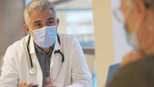 Doctor with face mask listening to patient in office, 19-ncov pandemic