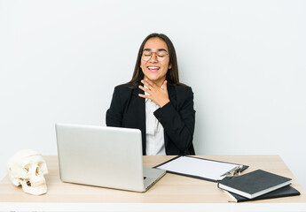 Young traumatologist asian woman isolated on white background laughs out loudly keeping hand on chest.