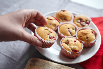 Strawberry muffin in hand on kitchen table background