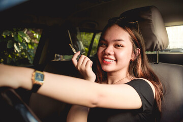 A young asian girl proudly shows the keys to her new car. Possible gift from parents or result of...