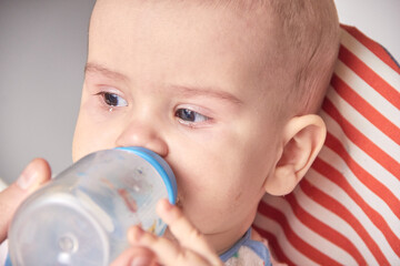 Giving to drink water baby from bottle, closeup