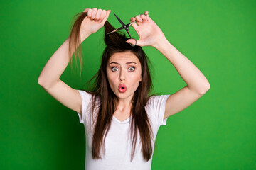 Photo portrait of surprised woman ready to cut own hair isolated on vivid green colored background