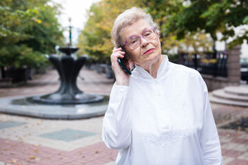 mature european woman talking on the phone in summer park