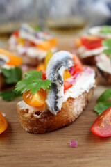 Bruschetta with light cheese, tomato and anchovy served with white wine on dark background. Top view with copy space.