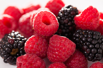handful of raspberry and blackberry berries on white background