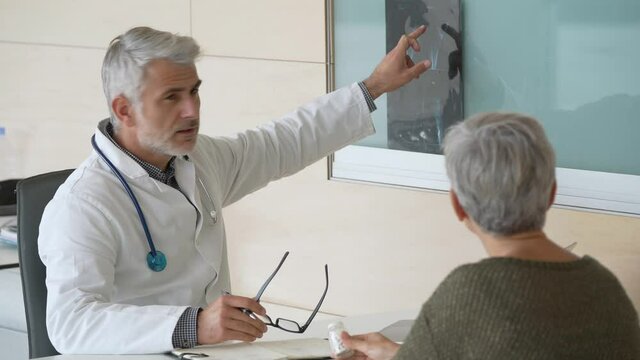 Mature doctor with patient in office, radiology