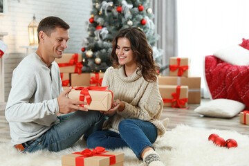Obraz na płótnie Canvas Happy couple with Christmas gift at home