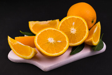 
Sliced ​​oranges on a white wooden board on a black background.
Close-up.