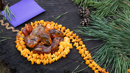 Yellow vintage Baltic royal amber necklace,  sparkling  pieces of amber and empty greeting card are nicely laid out on the dark stump. Amber is magic strength healing beauty powers  protection luck. 