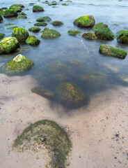 Pebble beach with rocks in the foreground against the sea. Cloudy day.