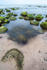 Pebble beach with rocks in the foreground against the sea. Cloudy day.