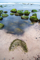 Pebble beach with rocks in the foreground against the sea. Cloudy day.