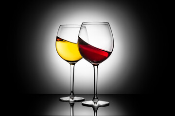 Splash of white and red wine in glasses on dark background