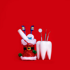 Dental Care Dentist Merry Christmas Card Tooth Model Santa's shoe With Presents And Dental Instruments On Red Background With Copy Space.