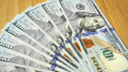 A stack of US dollars scattered on wooden boards
