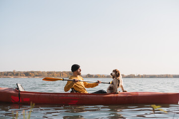 Kayaking with dogs: man rowing a boat on the lake with his spaniel. Active rest and adventures with pets, riding a canoe with dog
