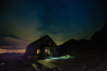 Mountain hut at night against a starry sky