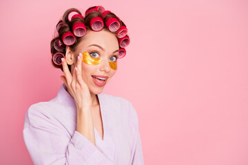 Portrait on delighted attractive lady arm touch under eye bag hair curlers isolated on pink color background