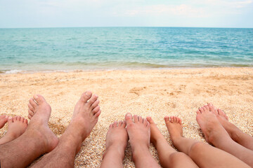 A Legs of the beautiful whole family on the sand near the sea background
