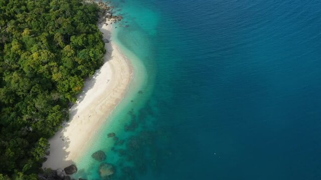 Wid cinematic drone shot of woman walking on Nudey Beach on Fitzroy Island