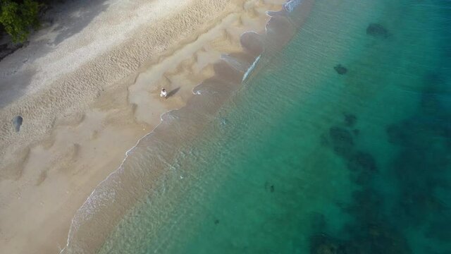 Downward angle rising drone shot of woman walking on Nudey Beach on Fitzroy Island