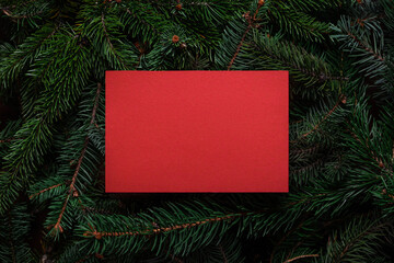 Fototapeta na wymiar Christmas tree branches with red paper card note. Nature New Year concept. Merry Christmas card, background. Congratulations, holidays, celebration. Mock up, copy space, flat lay.