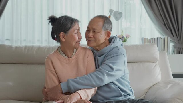 Portrait of Asian seniour couple hugging and sitting in living room.