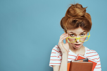 Female student with notepads and glasses hairstyle on her head teacher model blue background