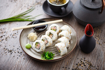 Sushi maki rolls California with crab, cucumber and avocado on a plate with chopsticks, soy sauce, wasabi and ginger. Japanese traditional seafood served for lunch in modern gourmet restaurant