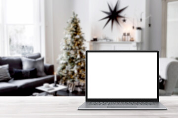 Blank display screen laptop computer on white wood table. Modern cozy comfortable home living room with Christmas decor. Home office desk workspace. Mock up copy space. Winter sales, online shopping