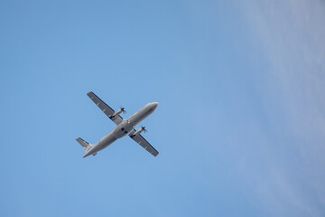  white propeller plane flies in the blue sky