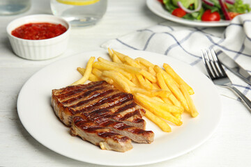 Grilled steak with French fries on white table