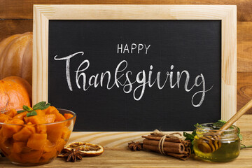 Thanksgiving greetings. Pumpkin with honey and spices, wooden board, top view. Kaligraphic capital inscription.