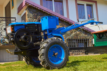 new two-wheeled tractor in the yard,blue new tractors near the house for agricultural work in the field