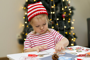 Toddler child girl making decorations for christmas . Concept of winter kids creativity and christmas craft. Christmas home time