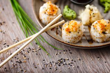 Baked sushi maki rolls with prawns and crab on a plate with chopsticks, soy sauce, wasabi and ginger. Japanese traditional fish food closeup served for lunch in modern gourmet restaurant
